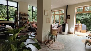 Un salon spacieux doté de grandes fenêtres, d’une cheminée et de différents types de sièges.