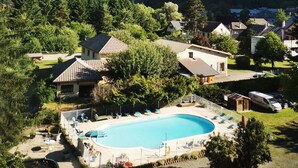 Un quartier résidentiel doté d’une piscine, entourée de maisons, d’arbres et bordé par un paysage montagneux.