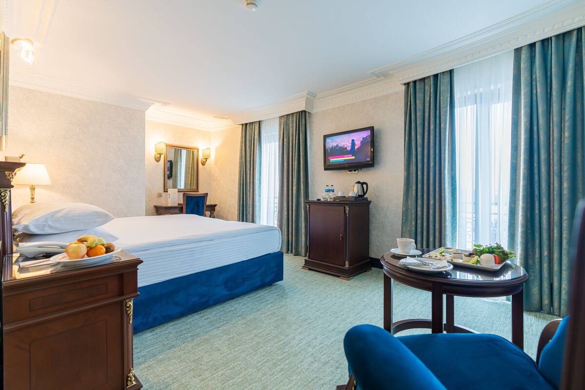 A hotel room with a bed, a desk, a TV, a coffee table, and a chair.