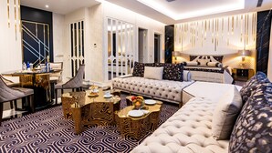 A modern hotel room with a large bed, a sofa, a dining area with a table, and a patterned carpet. - Ilci Residence Hotel (Ankara)