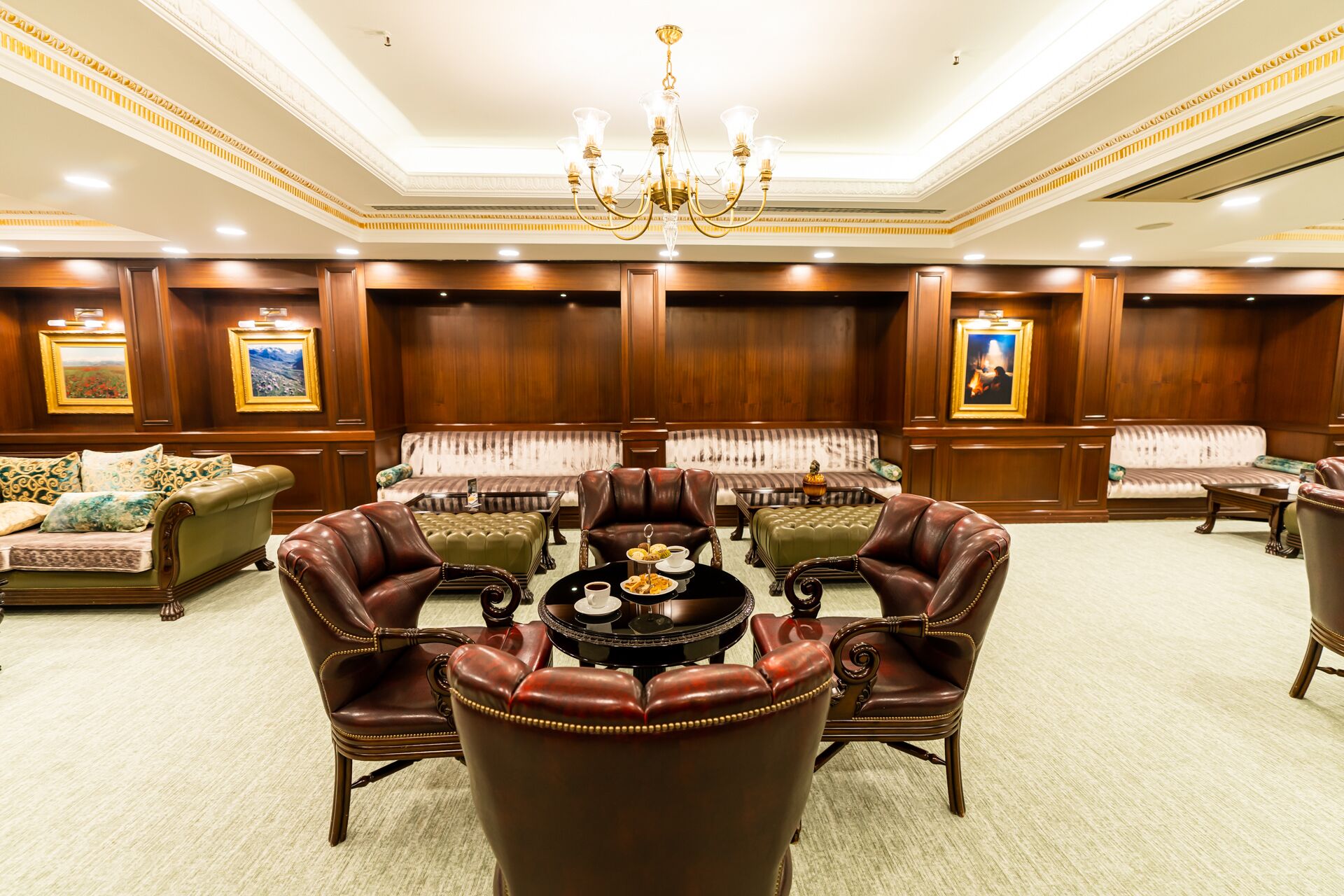 A luxurious lobby with leather armchairs, a central coffee table, and a chandelier.