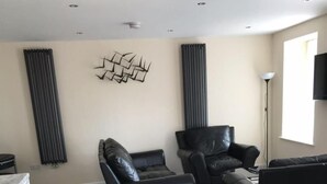A modern living room with a sectional sofa, a recliner, and a flat-screen TV mounted on the wall.