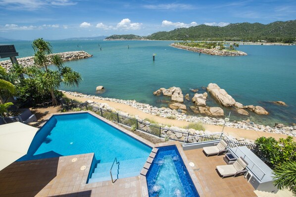 Zona de piscina con vista a un mar tranquilo e islas rocosas.