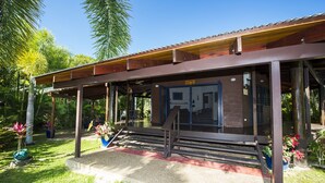 A covered outdoor area with a wooden deck, steps leading to a door, and potted plants. - Magnetic Cottage (Horseshoe Bay)