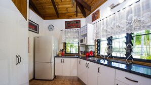 A kitchen with white cabinets, a refrigerator, a microwave, and a sink. - Magnetic Cottage (Horseshoe Bay)
