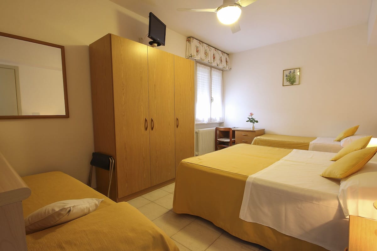 A bedroom with two beds, a wardrobe, a desk, and a chair.