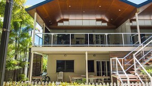 A two-story house with a balcony, a staircase, and a garden area. - Picnic Bay Apartments Unit 3 (Picnic Bay)
