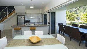 A modern kitchen with a dining area and a balcony. - Beachside Apartment 13 (Nelly Bay)