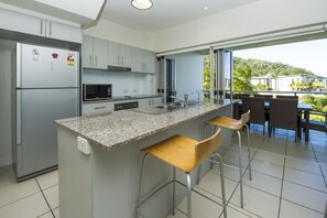 Een moderne keuken met een granieten aanrecht, roestvrijstalen apparatuur en uitzicht op een balkon met zitplaatsen.