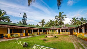 A resort with a central lawn marked "RESORT," surrounded by palm trees and a building with a tiled roof. - C'Roque Beach Resort (Colva)