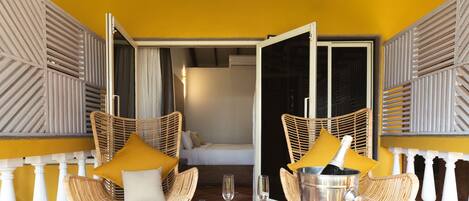 A balcony with wicker chairs, a table, and a minibar.