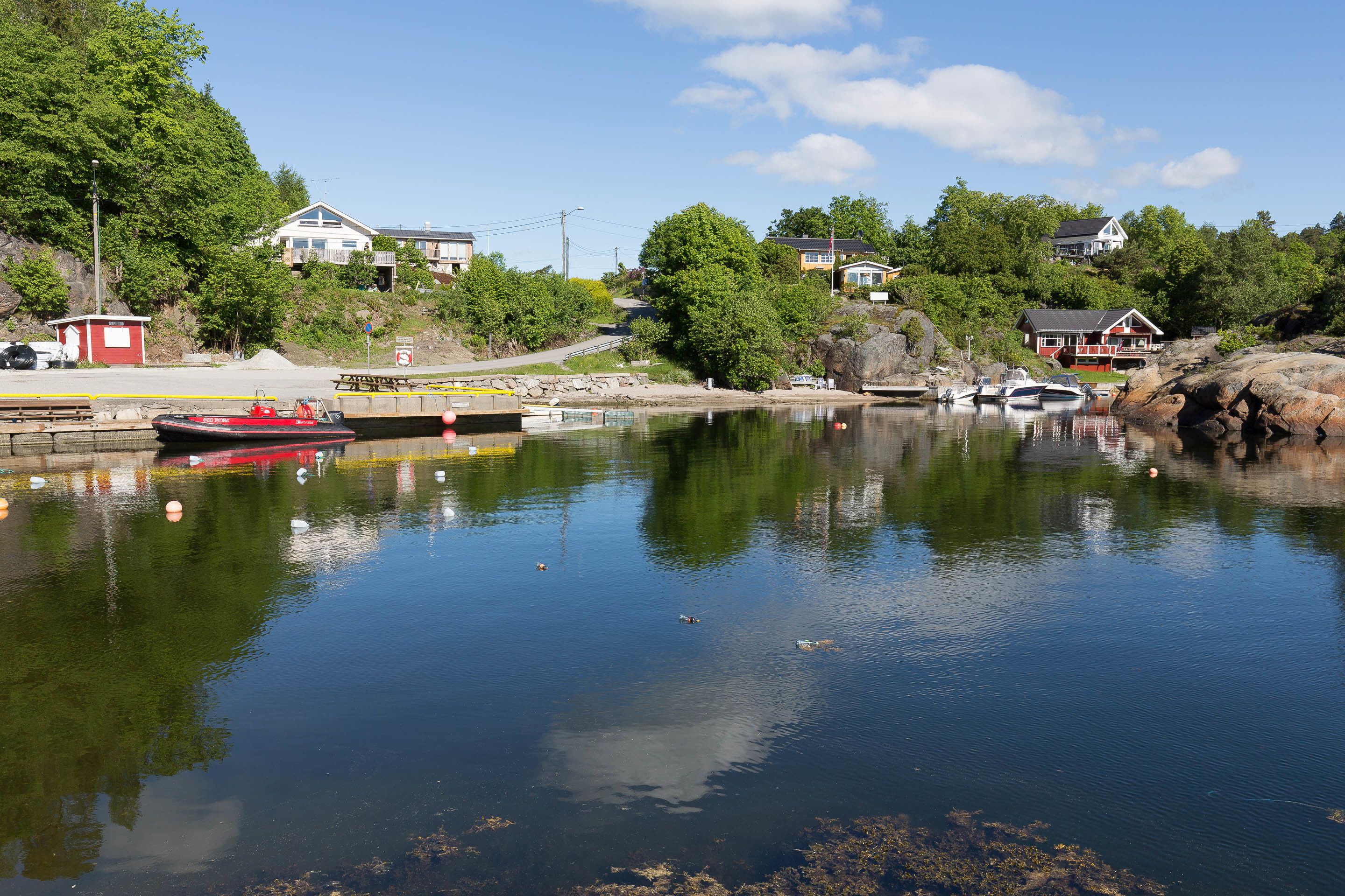 Ein ruhiger See mit vertäuten Booten, umgeben von Häusern und viel Grün.