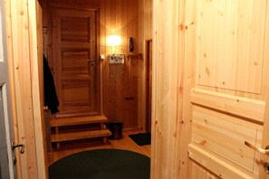 A wooden interior hallway with a door, a bench, a trash bin, and a small rug. - Lilleset Cabin - Gol (Gol)