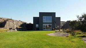 A modern two-story building with a flat roof, large windows, and a well-maintained lawn in front. - Haver Cabin - Sirevåg (Ha)