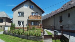 A two-story residential building with a balcony, a gated entrance, and a well-maintained lawn. - Apartments Majercak (Zuberec)