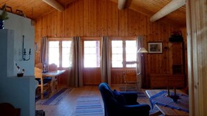 Ein Interieur einer Holzhütte mit Essbereich, einer Couch und einem Tisch mit Kerzen.