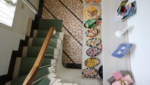 A staircase with green carpeted steps leading to a landing with a patterned wall. - B&B Ortensia (Forte dei Marmi)
