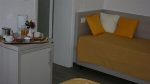 A bedroom with a bed, a bedside table with a cup, a vase with flowers, and a tray with breakfast items. - B&B Ortensia (Forte dei Marmi)