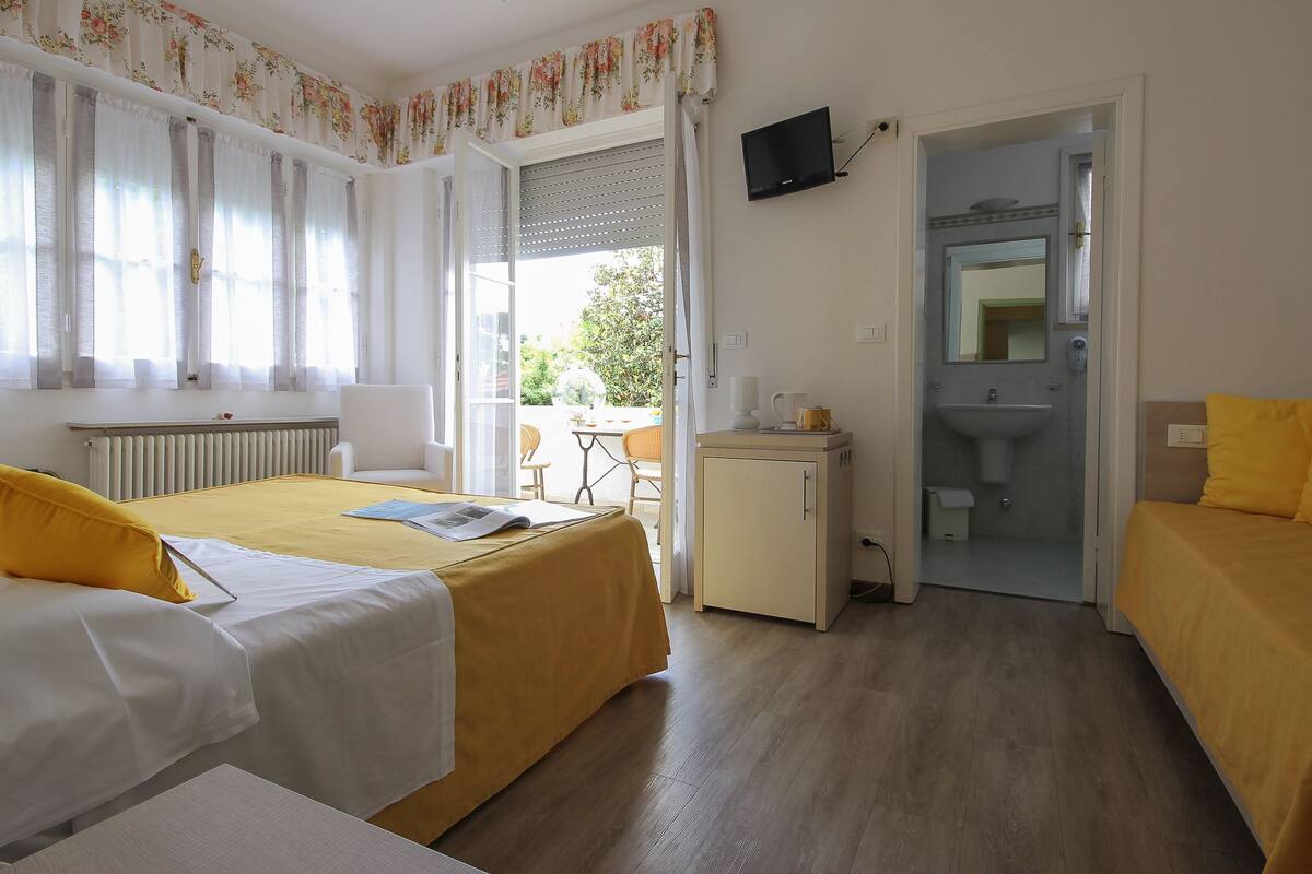 A hotel room with two beds, a desk, a TV, and a bathroom.