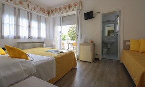 Ein Hotelzimmer mit zwei Betten, einem Schreibtisch, einem Fernseher und einem Badezimmer.