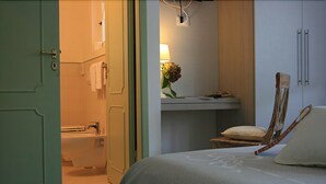 A hotel room with a bed, a bathroom with a bathtub, and a chair. - B&B Ortensia (Forte dei Marmi)