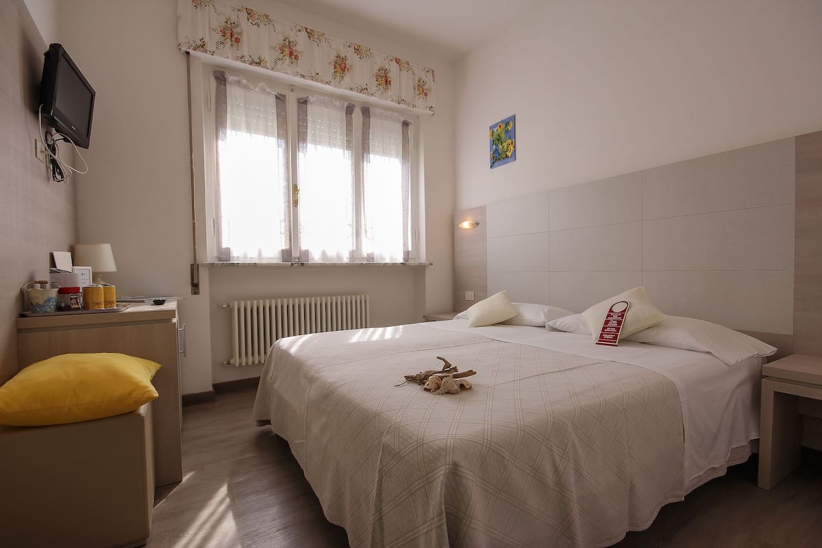 A neatly arranged bedroom with a bed, bedside table, and a window with curtains.