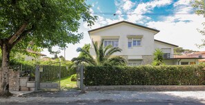 A two-story house with a gated entrance, surrounded by greenery and a clear sky. - B&B Ortensia (Forte dei Marmi)