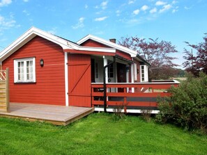 Una casa de madera roja con porche y una pequeña terraza.