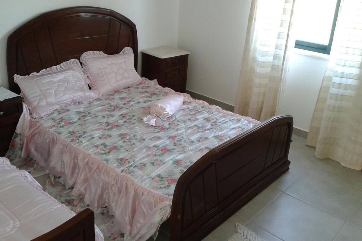 A bedroom with a wooden bed, floral bedding, and a nightstand.