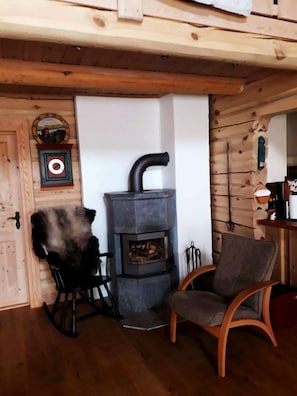 A cozy room with a stone fireplace, wooden walls, a rocking chair, and a chair. - Blazerbu - Cabin for 8 persons - Hol (Hol)