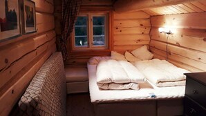 A cozy log cabin bedroom with a bed, a bench, a dresser, and a window with a curtain. - Blazerbu - Cabin for 8 persons - Hol (Hol)