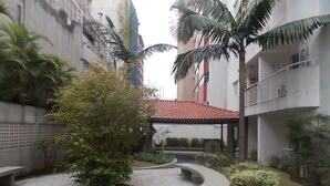 A courtyard with a central gazebo, surrounded by palm trees and a paved walkway. - Apartamento 2 dorms Metrô Saúde (São Paulo)