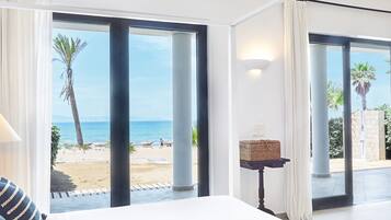 Une chambre d’hôtel avec un grand lit, une vue sur la plage et une petite table avec une lampe.