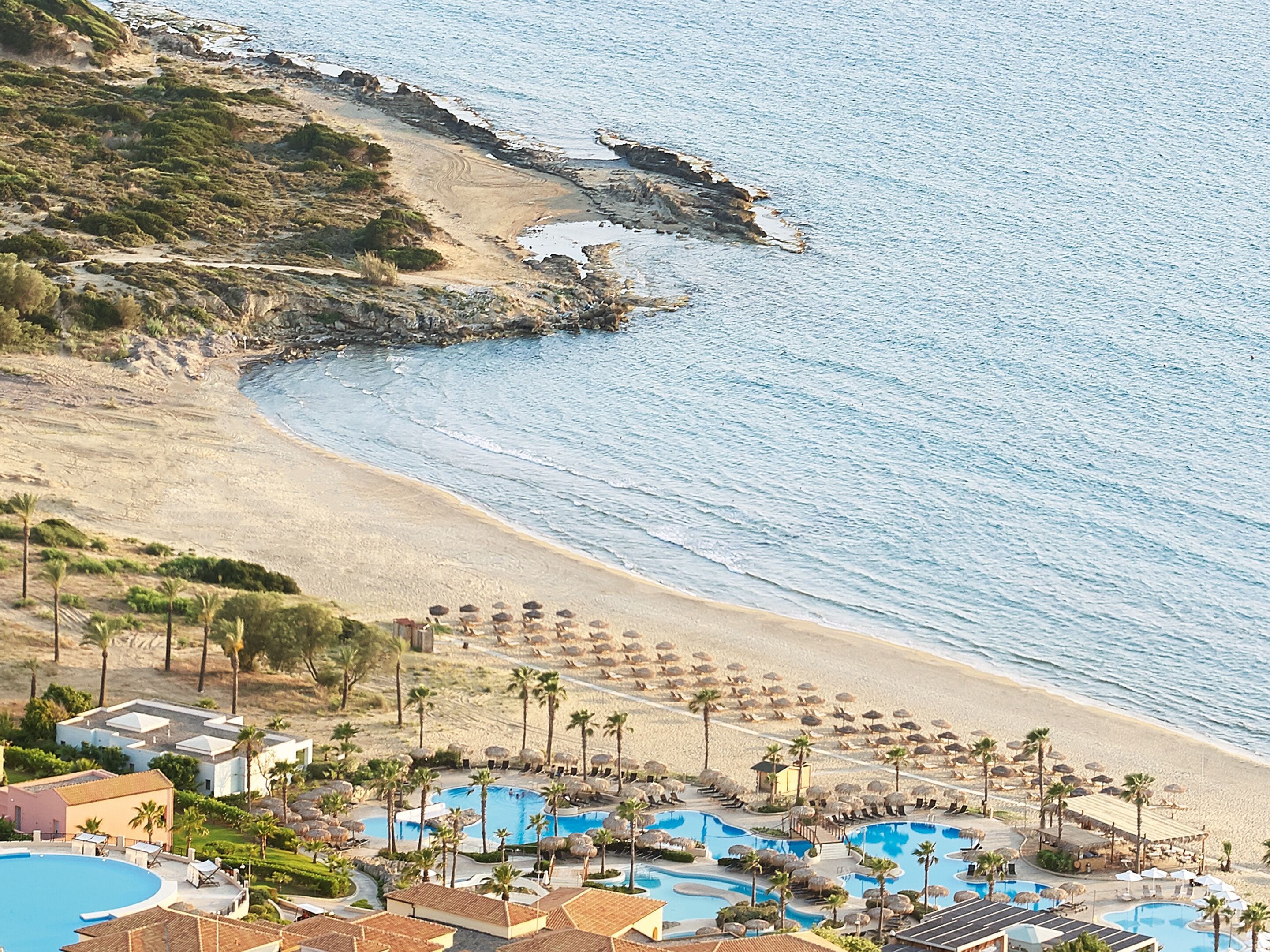 A resort with multiple swimming pools, beach access, and a rocky coastline.