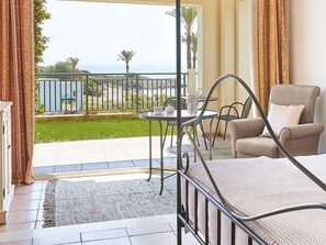 Una habitación con cama, una mesa y sillas, vista al mar y un balcón con barandilla.