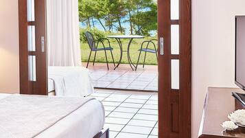 A hotel room with a bed, a TV, and a view of a patio with chairs and a table.