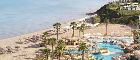 A resort with multiple swimming pools, a beach, and palm trees.