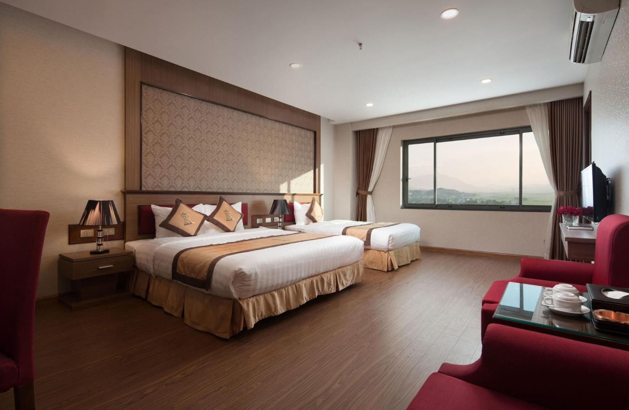 A hotel room with two beds, a desk, a chair, and a large window with a view.