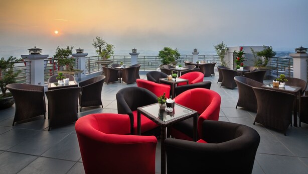 Terraza en la azotea con mobiliario de mimbre y sillas rojas, con vistas panorámicas.