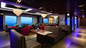 Un salón moderno con una zona de estar central, ventanas amplias y luminarias contemporáneas.