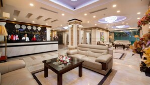 Un vestíbulo de hotel con mostrador de recepción, zona de estar y un candelabro.
