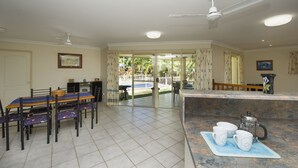 A spacious dining area with a table and chairs, a coffee station, and a view of the outdoors. - Island Dreams (Nelly Bay)