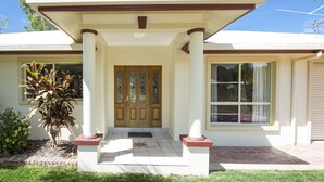 A two-story house with a front porch, a central entrance with a double door, and a large window on the right side. - Island Dreams (Nelly Bay)