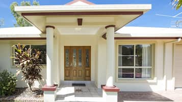 A two-story house with a front porch, a central entrance with a double door, and a large window on the right side.