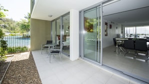 A modern hotel room with a balcony, a dining area, and a view of the marina.
