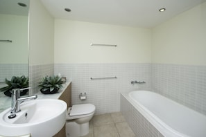 A modern bathroom with a sink, toilet, and bathtub.