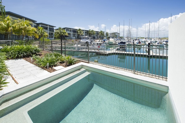 A swimming pool with a view of a marina and buildings in the background.