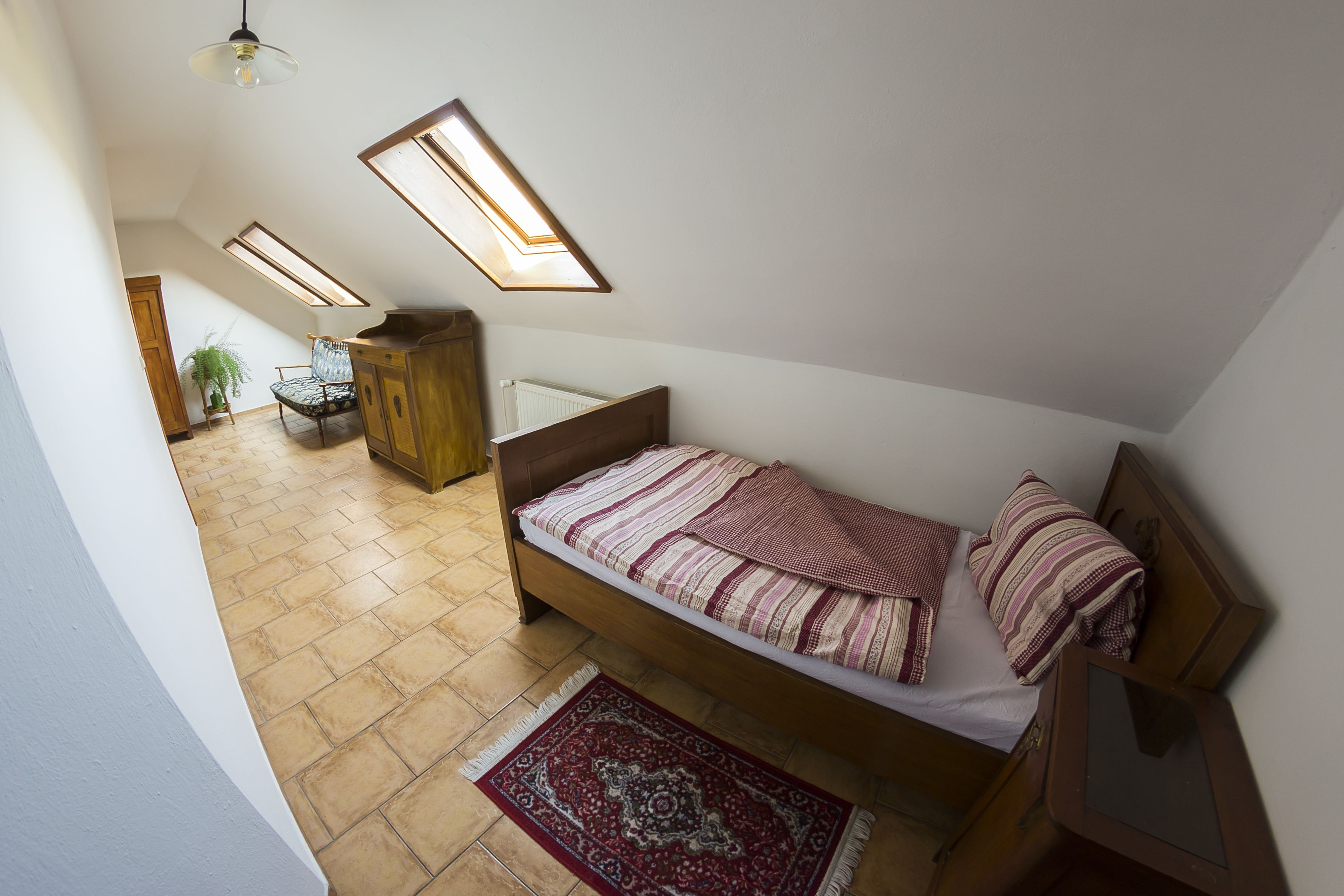Un dormitorio con cama, un armario de madera, un radiador y una planta en maceta.
