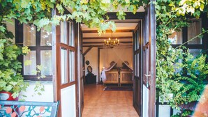 Un umbral abierto que da a una habitación con candelabro, vigas de madera y suelo de baldosas.
