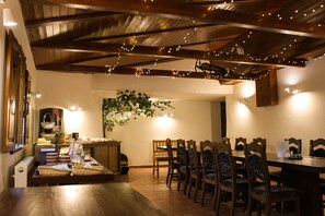 Un comedor con mesas y sillas de madera, luces colgantes y una planta suspendida.